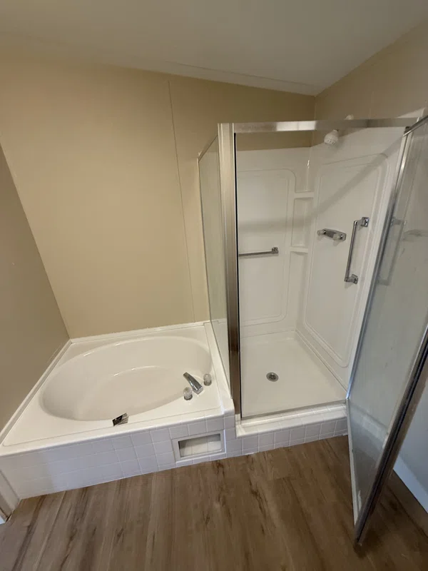 White oval soaking tub beside a separate shower enclosure.