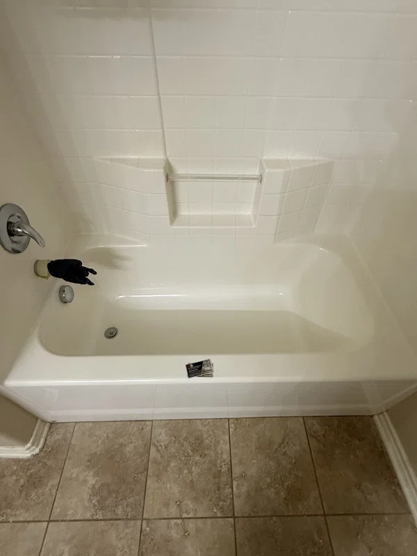 Light-colored bathtub and molded surround with shelves.