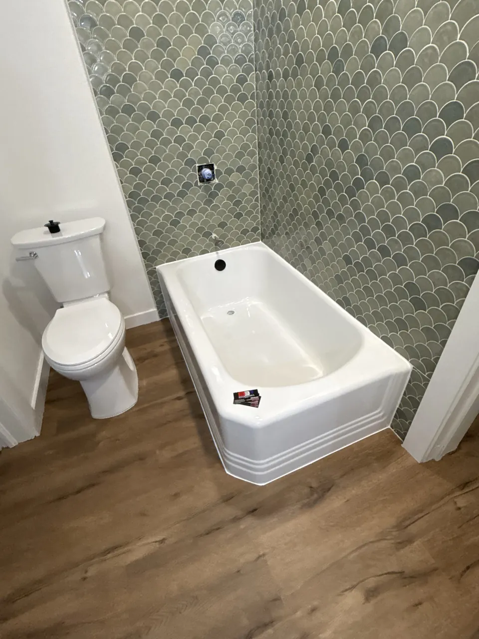 Refinished antique cast-iron bathtub beside green patterned tile in Nacogdoches, Texas.