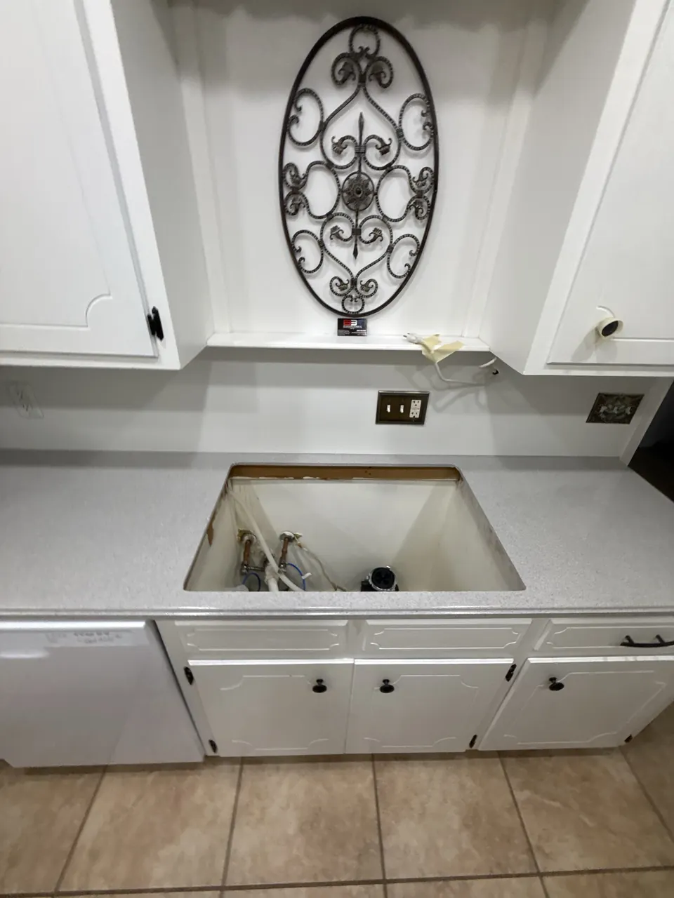White kitchen cabinets and speckled countertop around sink opening